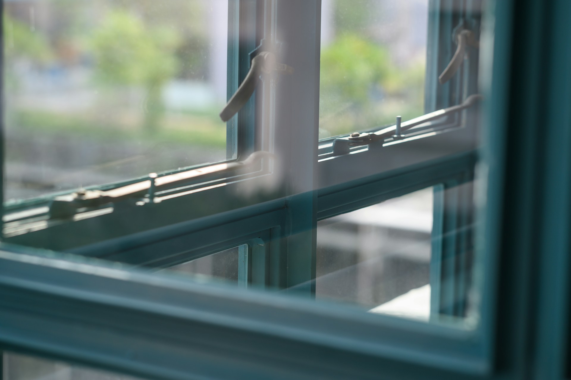 Close-up van metalen raamprofielen met glas in een modern interieur, met zicht op de buitenwereld